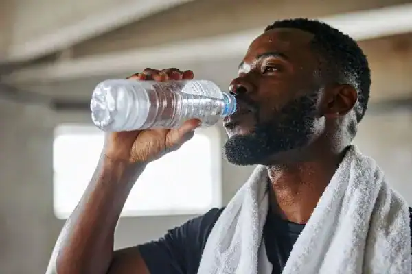 Image of man drinking water to improve hydration Aldershot after work out.